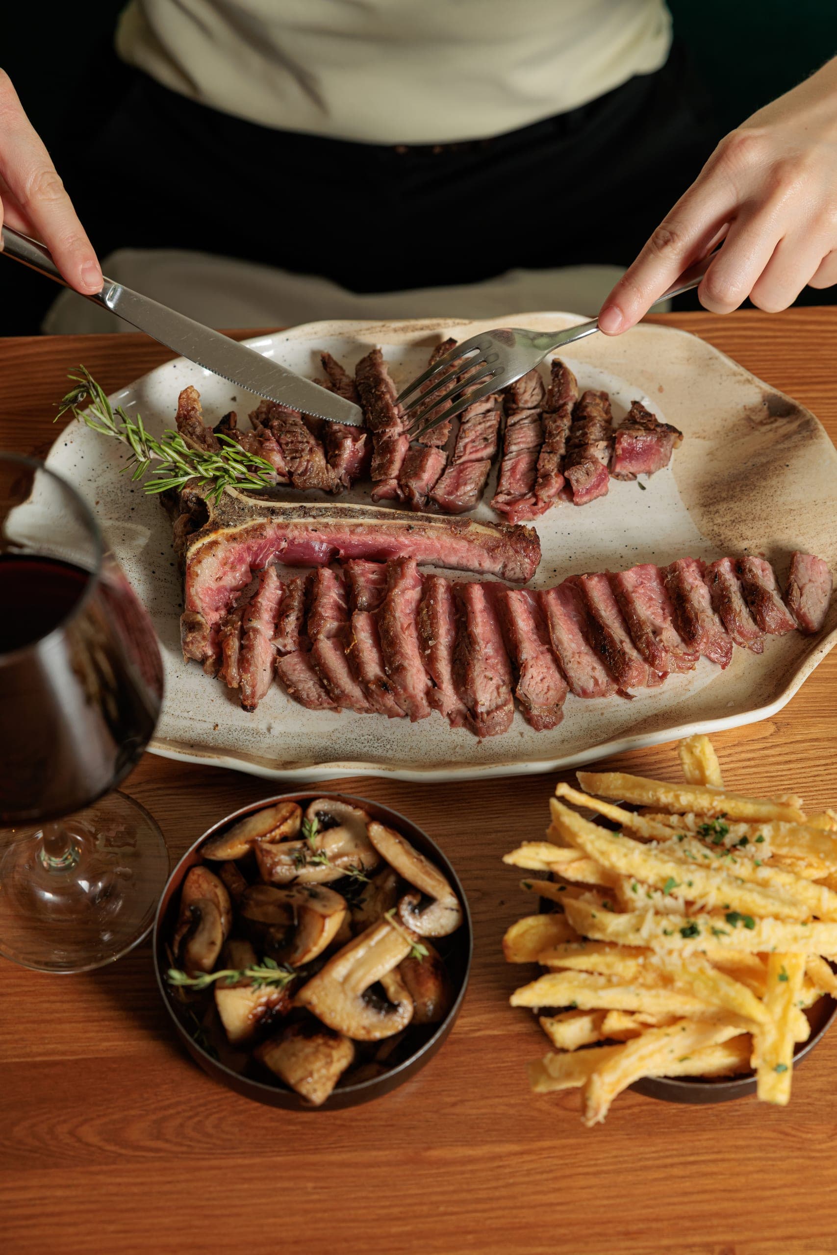 Sliced Fiorentina T-bone steak served with sauteed mushrooms and truffle parmesan fries