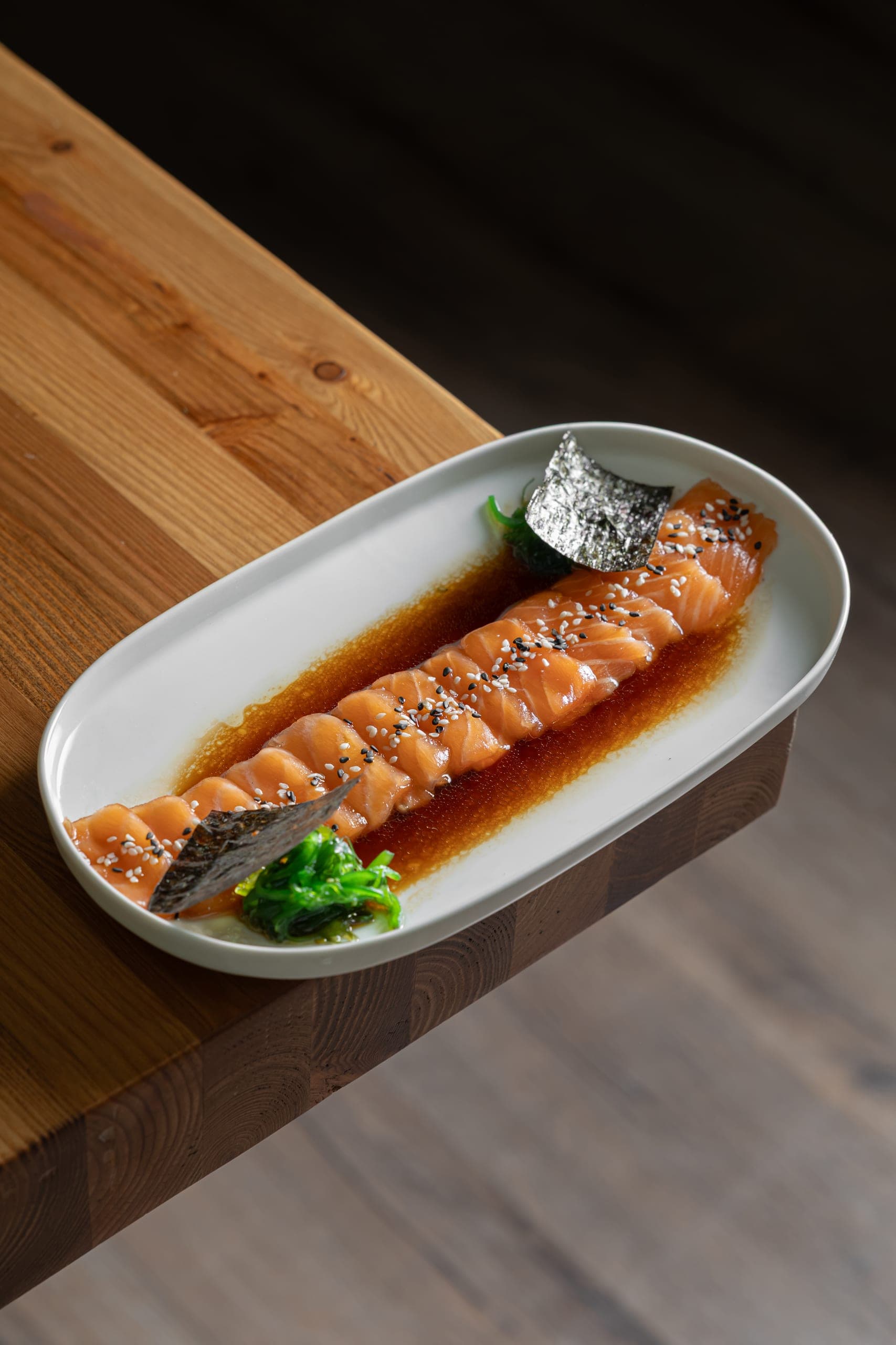 Salmon sashimi platter with nori and seaweed salad on a wooden table